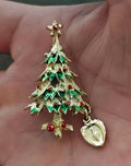 Green enamel Christmas tree brooch with red details and dangling heart medal charm