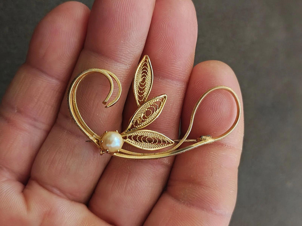 Gold tone leaf filigree brooch with faux pearl bead, front filigree detail, close-up