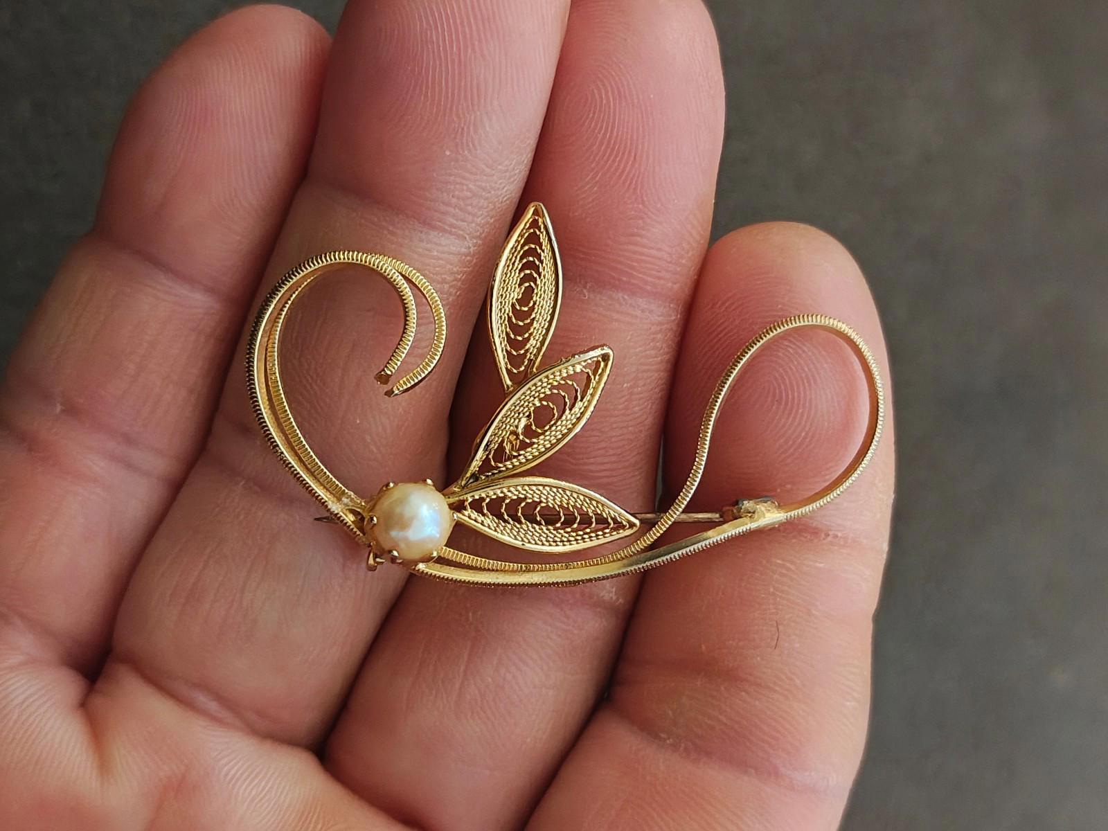 Gold tone leaf filigree brooch with faux pearl bead, front filigree detail, close-up