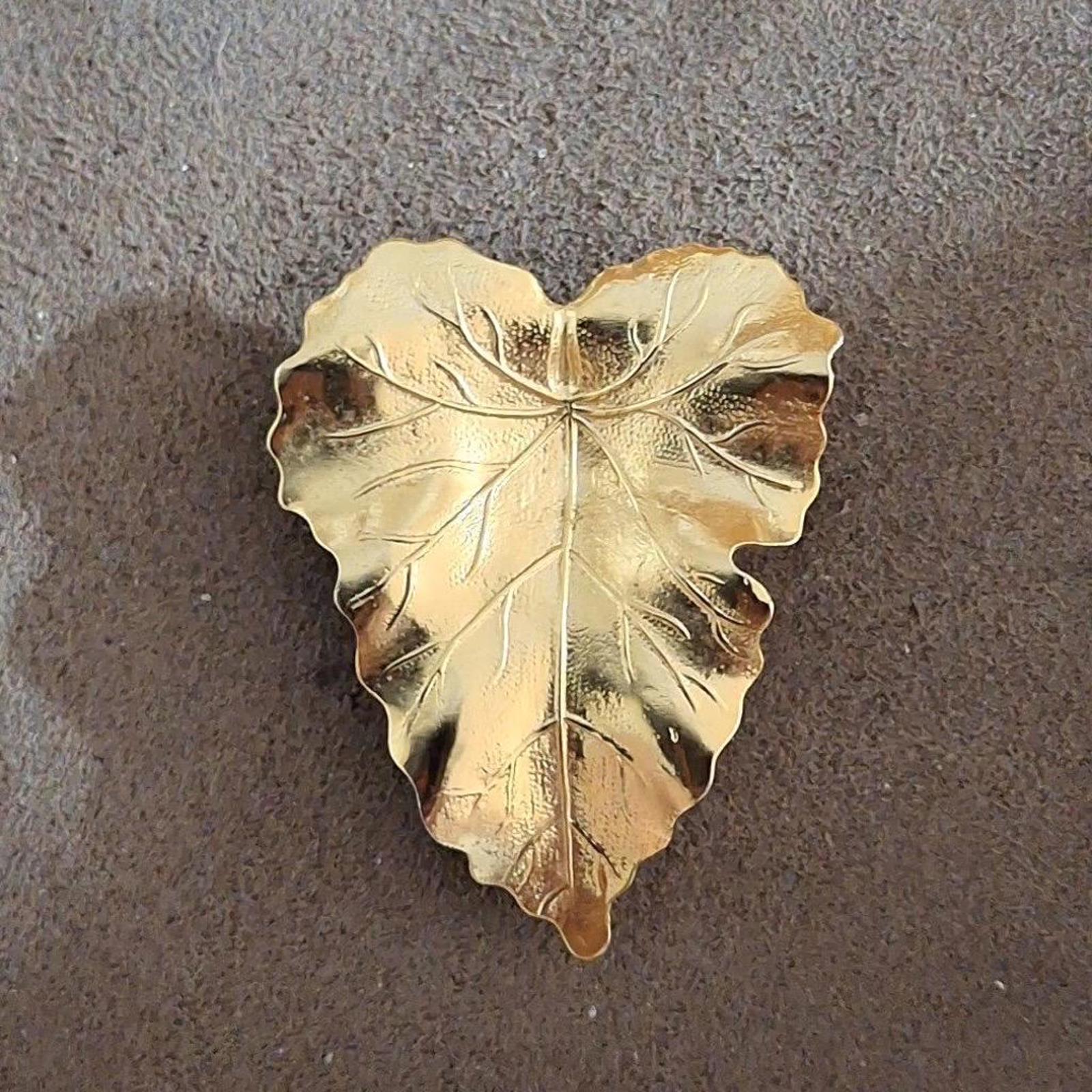 Gold-tone textured leaf scarf clip with raised vein detailing, lying flat