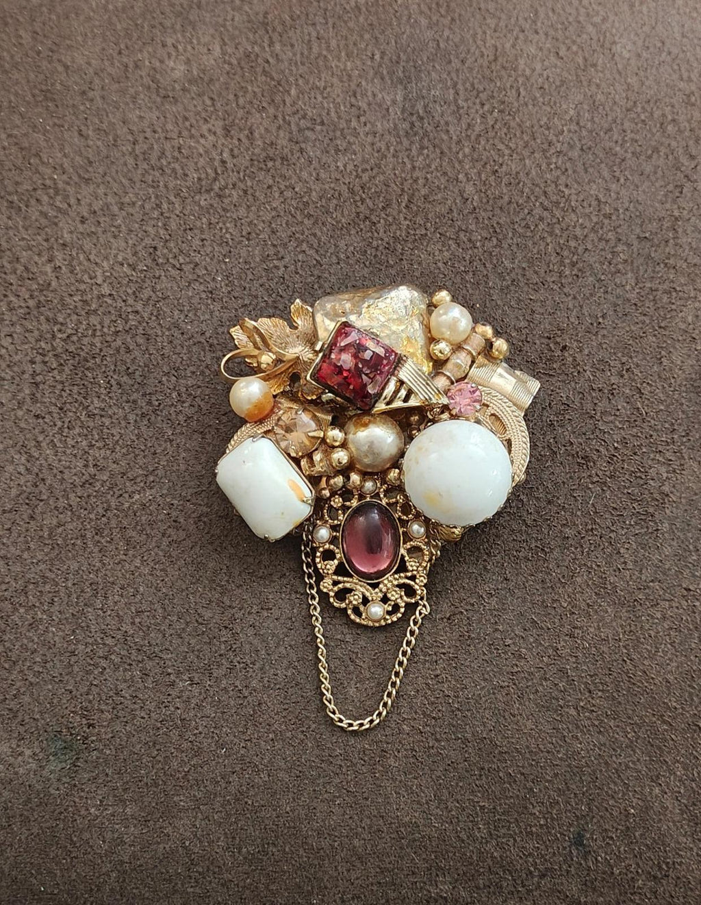 Gold-tone beaded brooch with faux pearls, white stones, red square crystal, and dangling chain