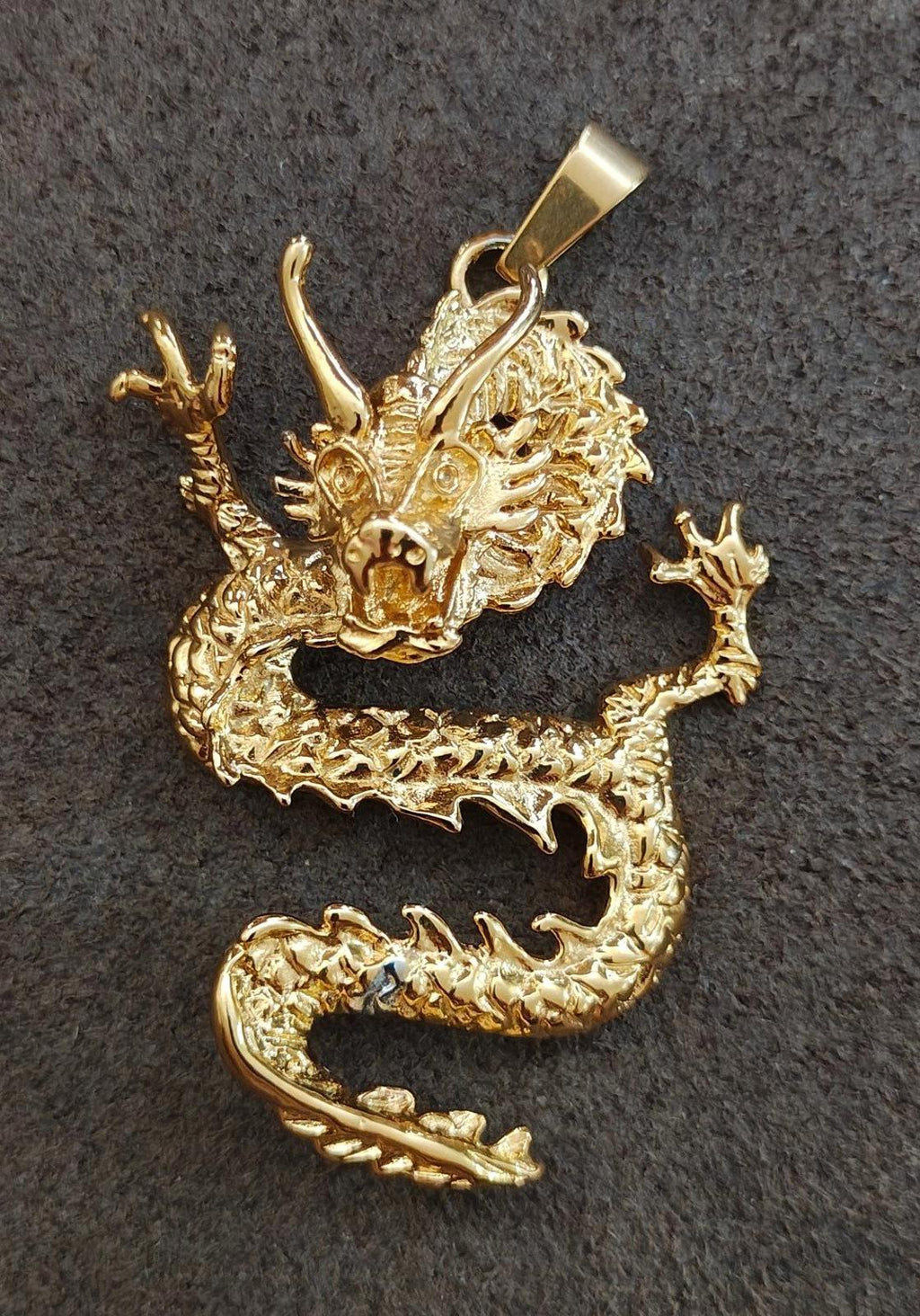 Gold-tone dragon pendant lying flat, detailed claws and curled tail with bail loop