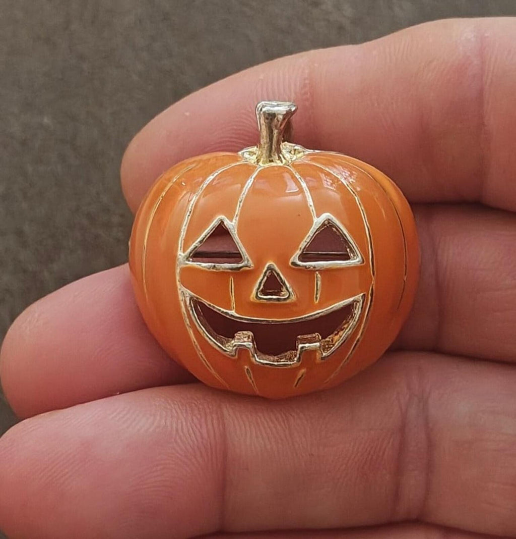 Orange jack-o'-lantern pumpkin brooch pendant with silver-tone face and stem
