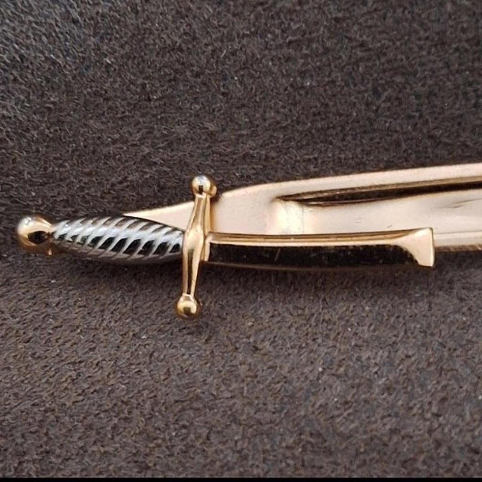 Gold pirate sword tie clip bar close-up of ribbed handle and crossguard