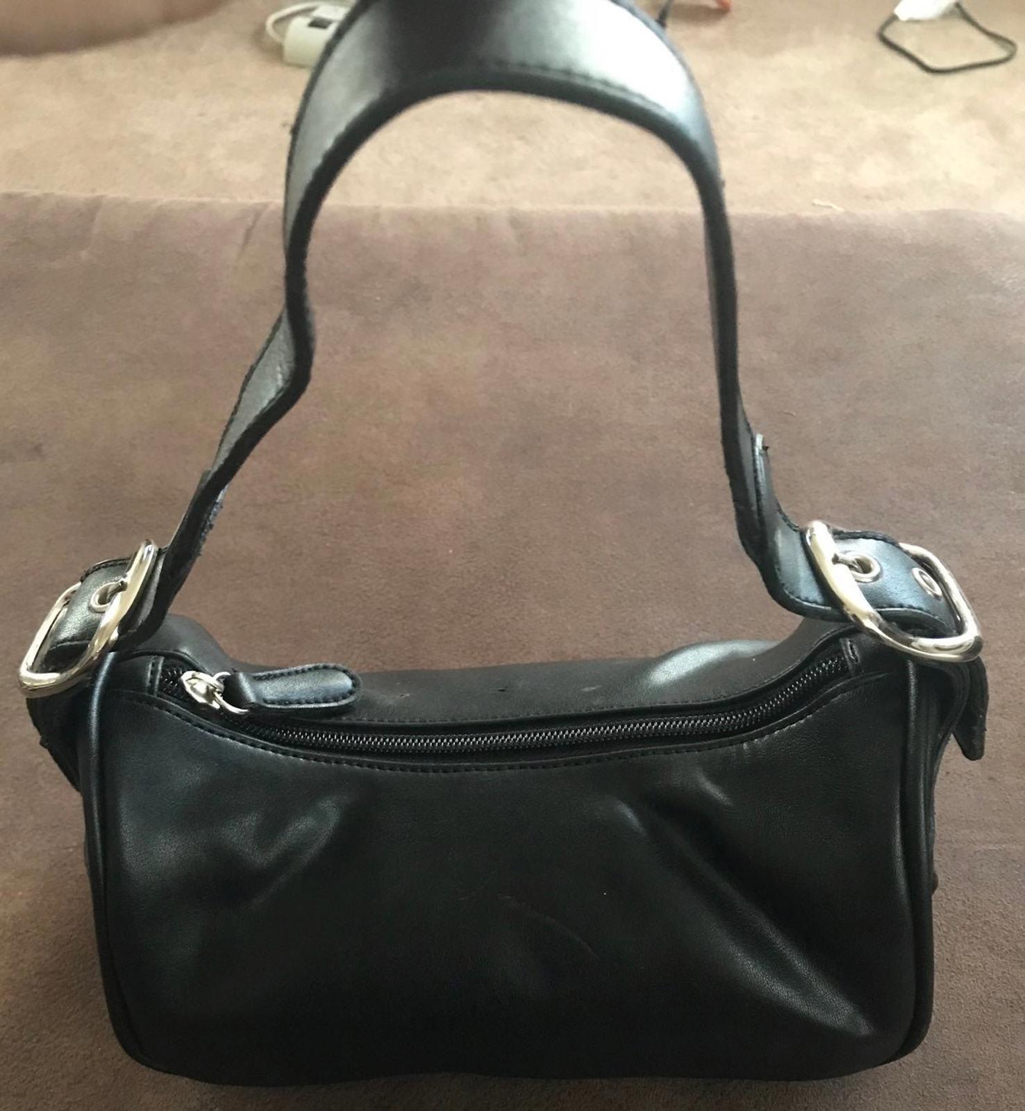 Black leather shoulder purse with top zipper and metal buckle strap hardware