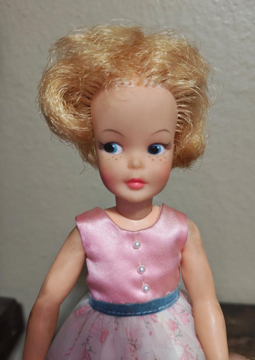 Vintage pepper doll face with blonde yarn hair, pink sleeveless top, floral skirt, blue belt