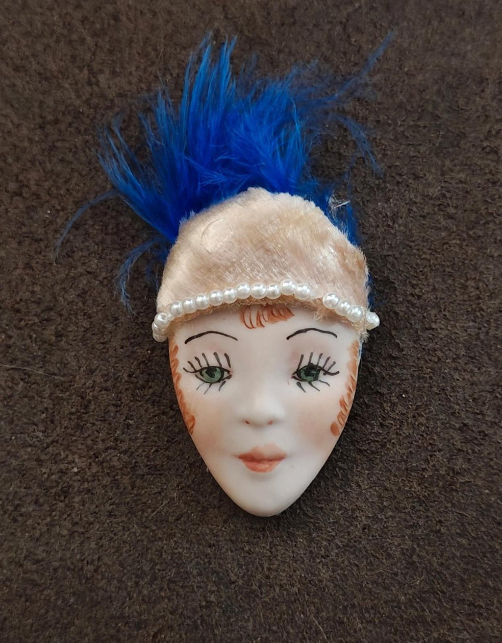 Doll face pin brooch with blue feather plume and cream beaded head wrap