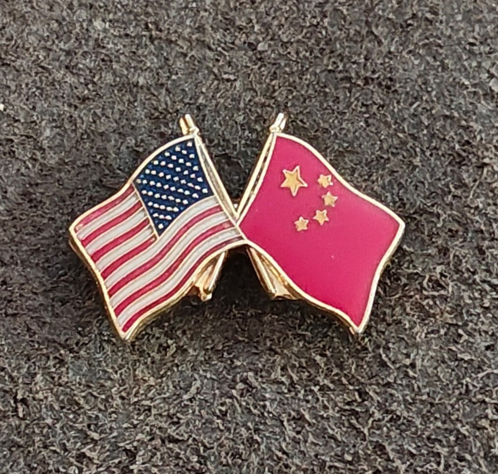 Crossed US and pink China flags enamel lapel pin with gold borders and star accents.