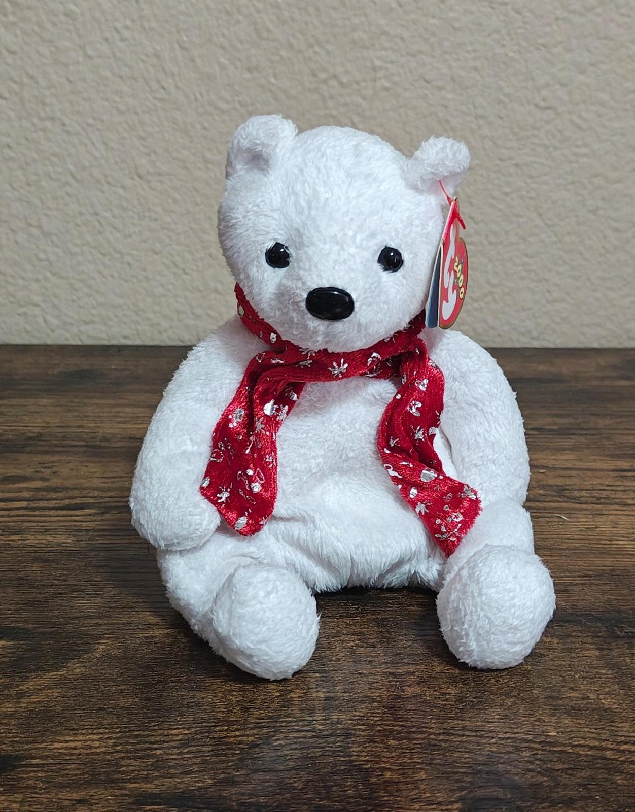 White bear plush sitting with red holiday scarf and small gift tag