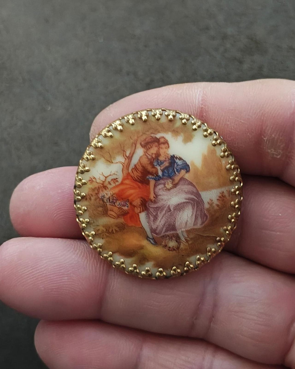Gold oval porcelain cameo brooch with painted couple and floral detail around them