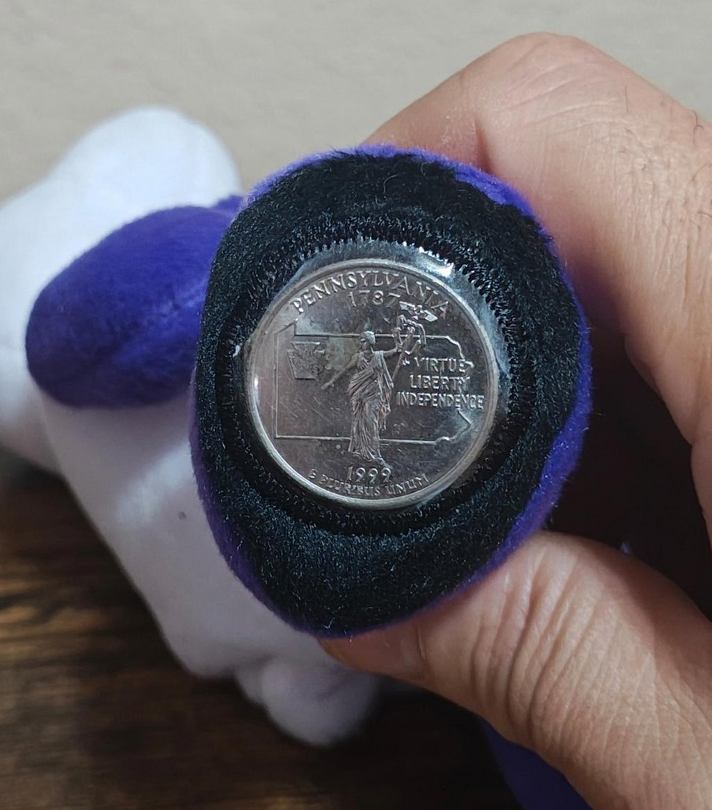 Close-up of coin medallion set into purple paw of bear plush