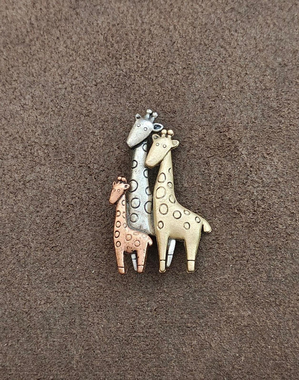 Tricolor giraffe family brooch with three standing giraffes: light blue, gold, and brown