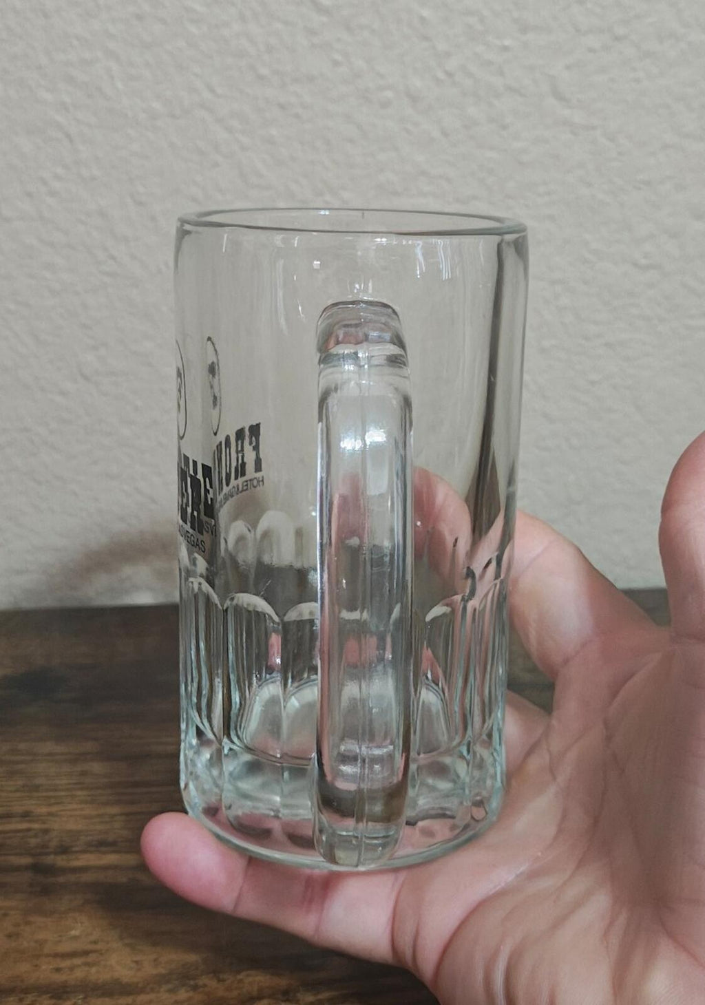Clear glass beer mug with embossed base and handle, logo visible