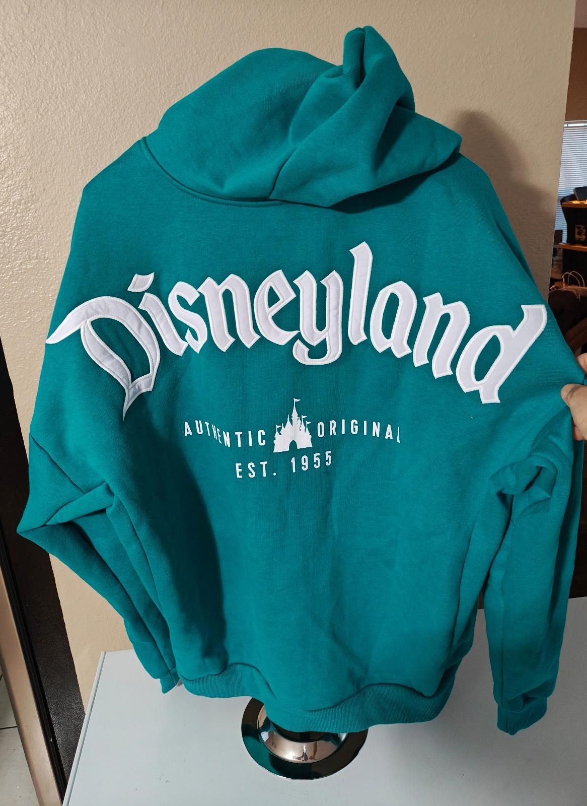 Teal zip-up hoodie with “Disneyland” text and “Est. 1955” on the back