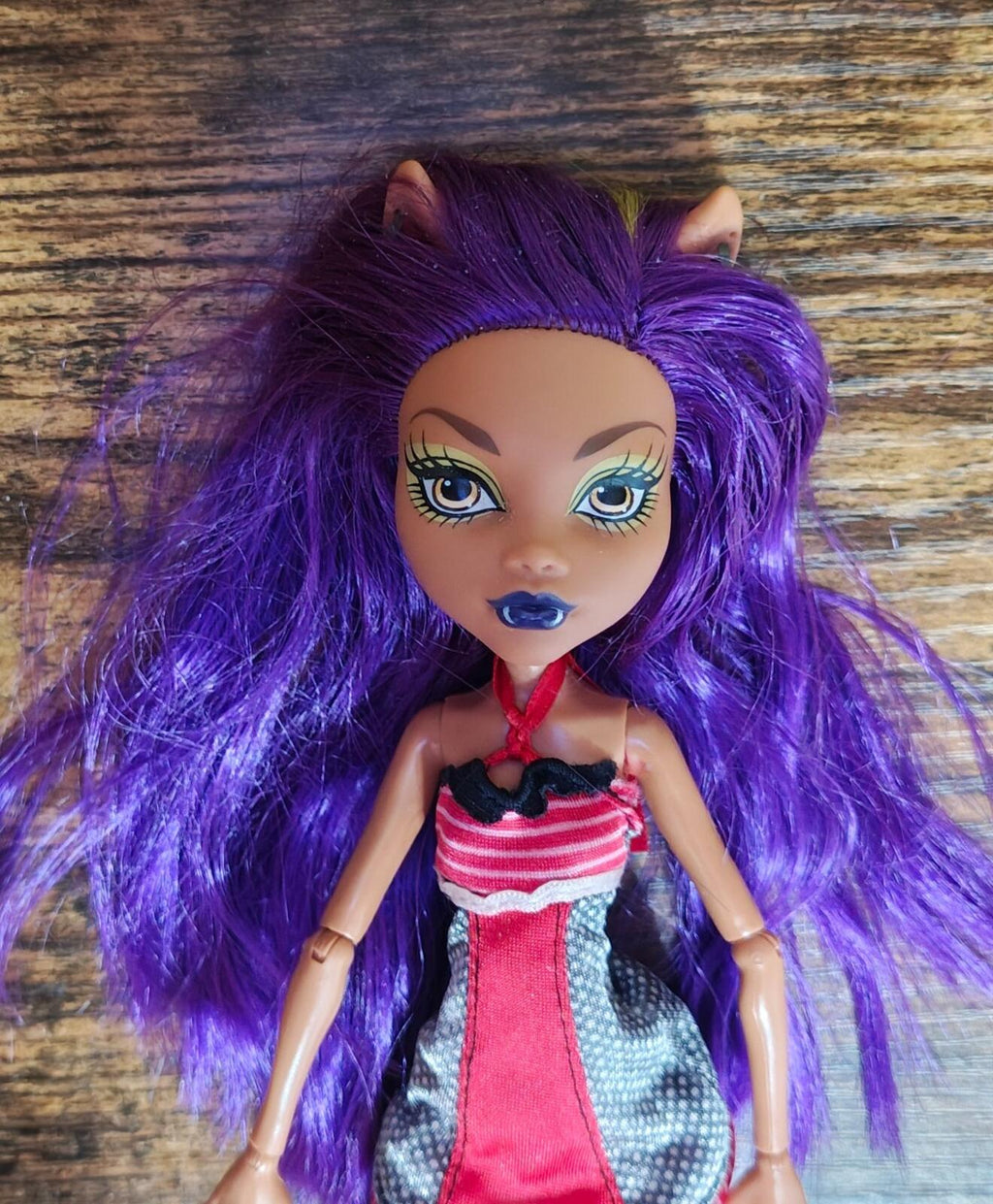 Purple-haired fashion doll close-up in red-and-black dress with striped bodice