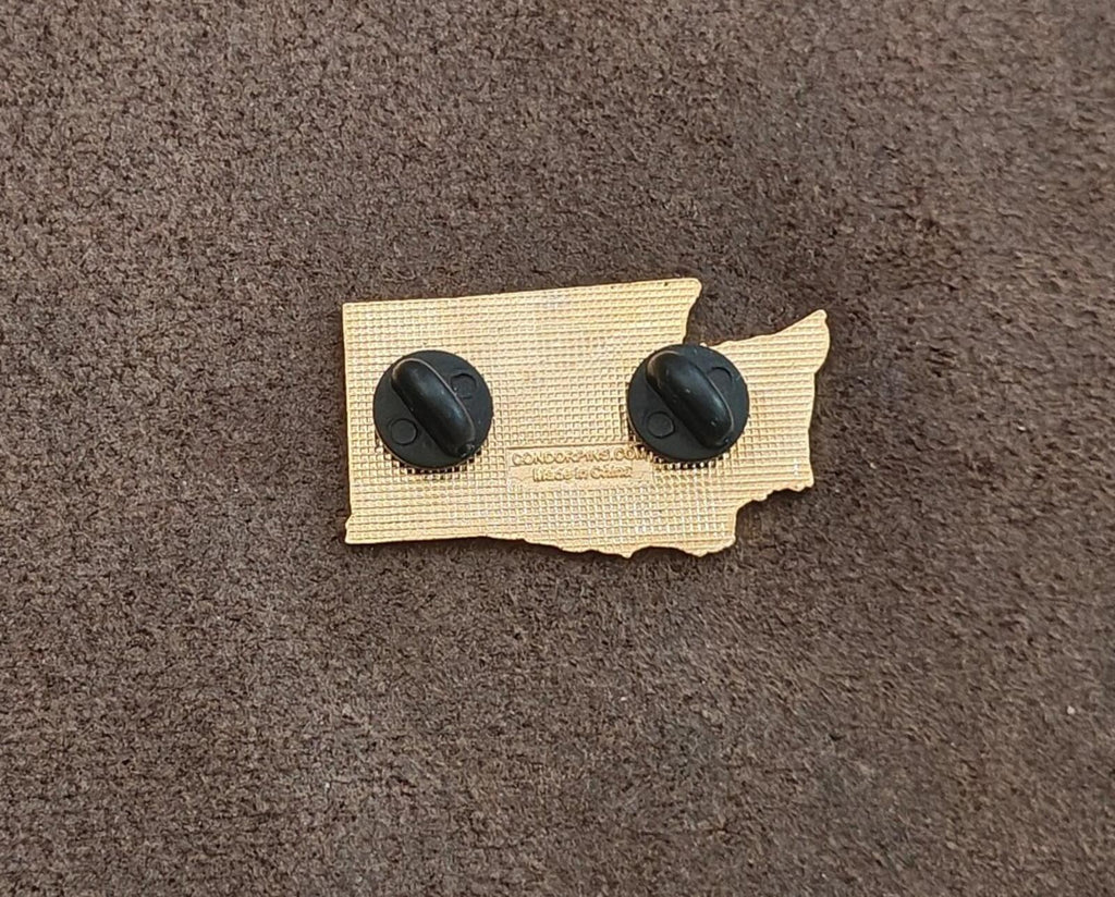 Back of green enamel pin on beige backing with two black posts