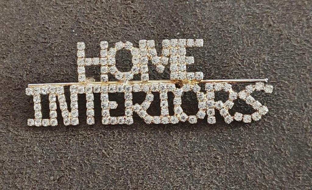 Rhinestone gold-tone brooch with "HOME" on top and "INTERIORS" below