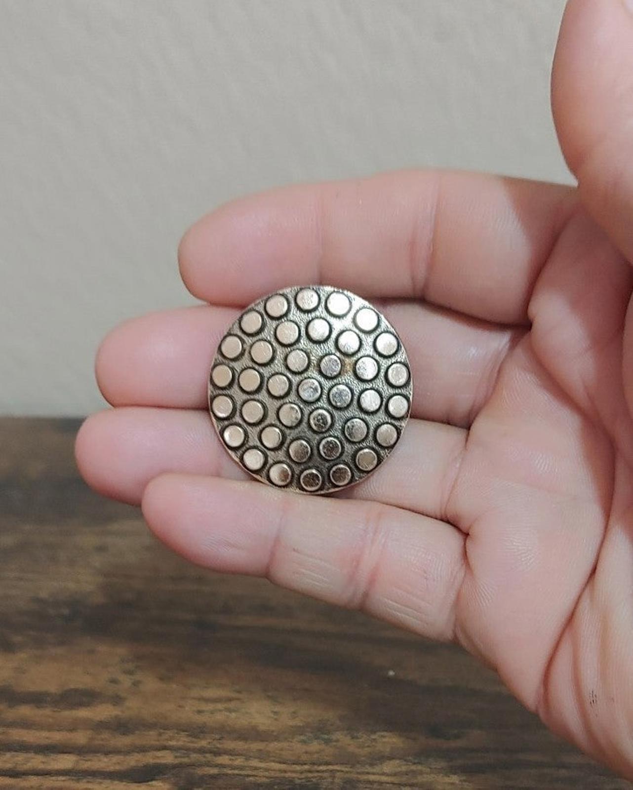 Circular scarf clip front with silver tone dotted design and textured rim