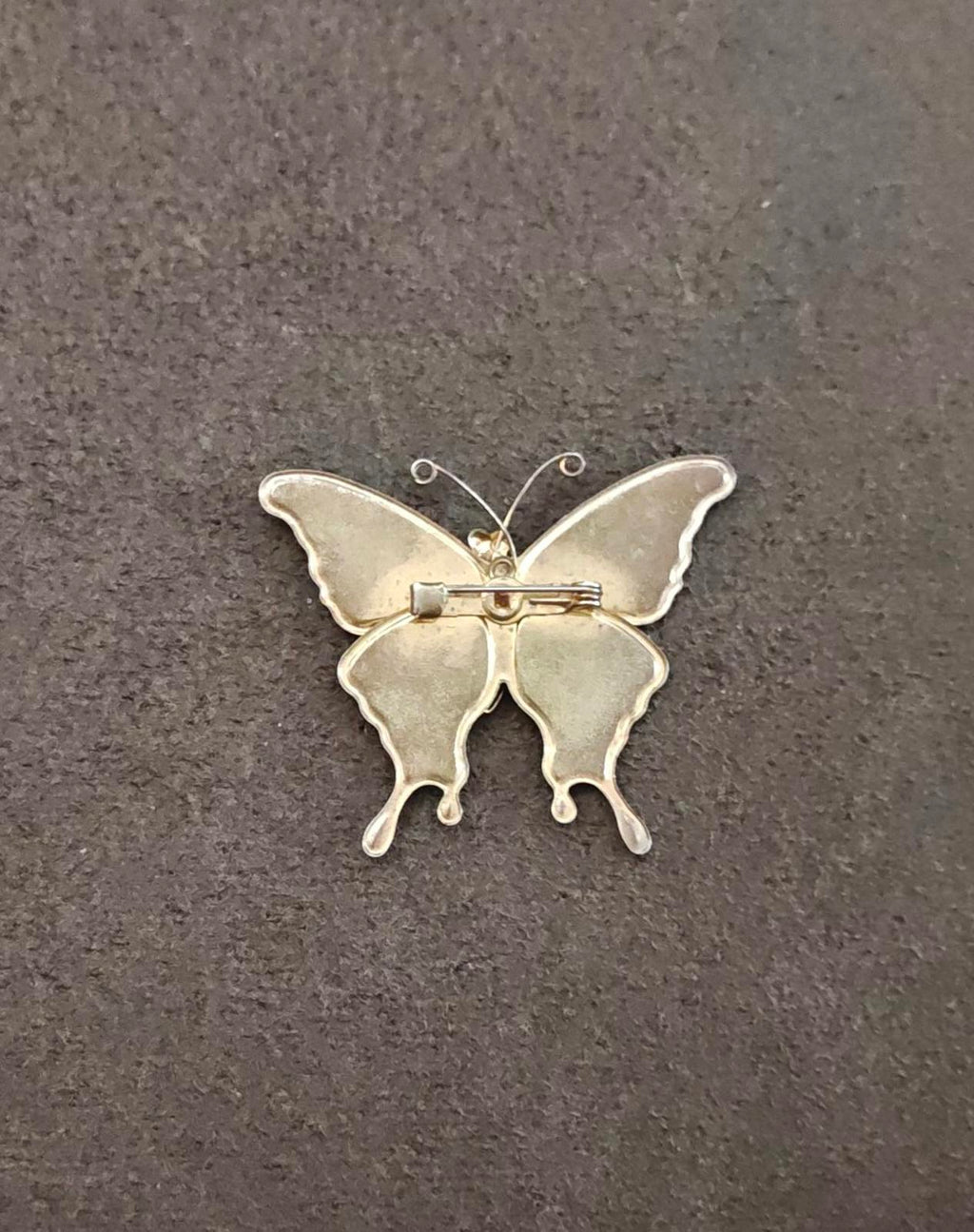 Butterfly brooch back view with pin clasp, gold-tone metal and oval wing outline