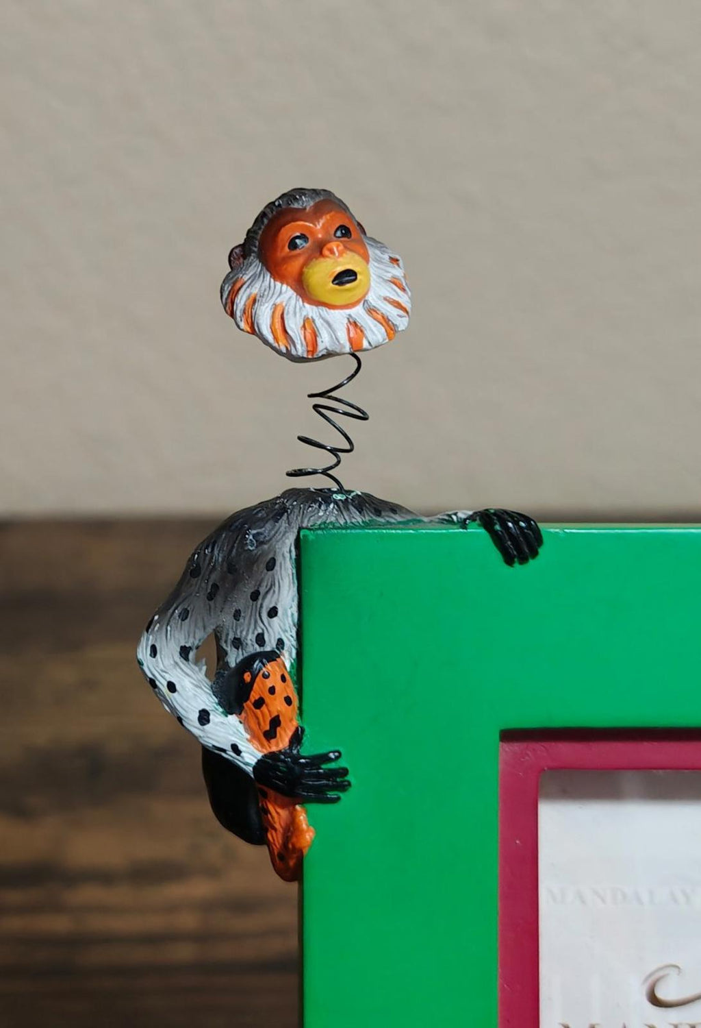 Green photo frame corner detail with monkey figurine on spring coil
