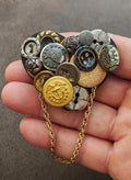Gold-tone button collage brooch with chain, featuring mixed round and coin-like pieces
