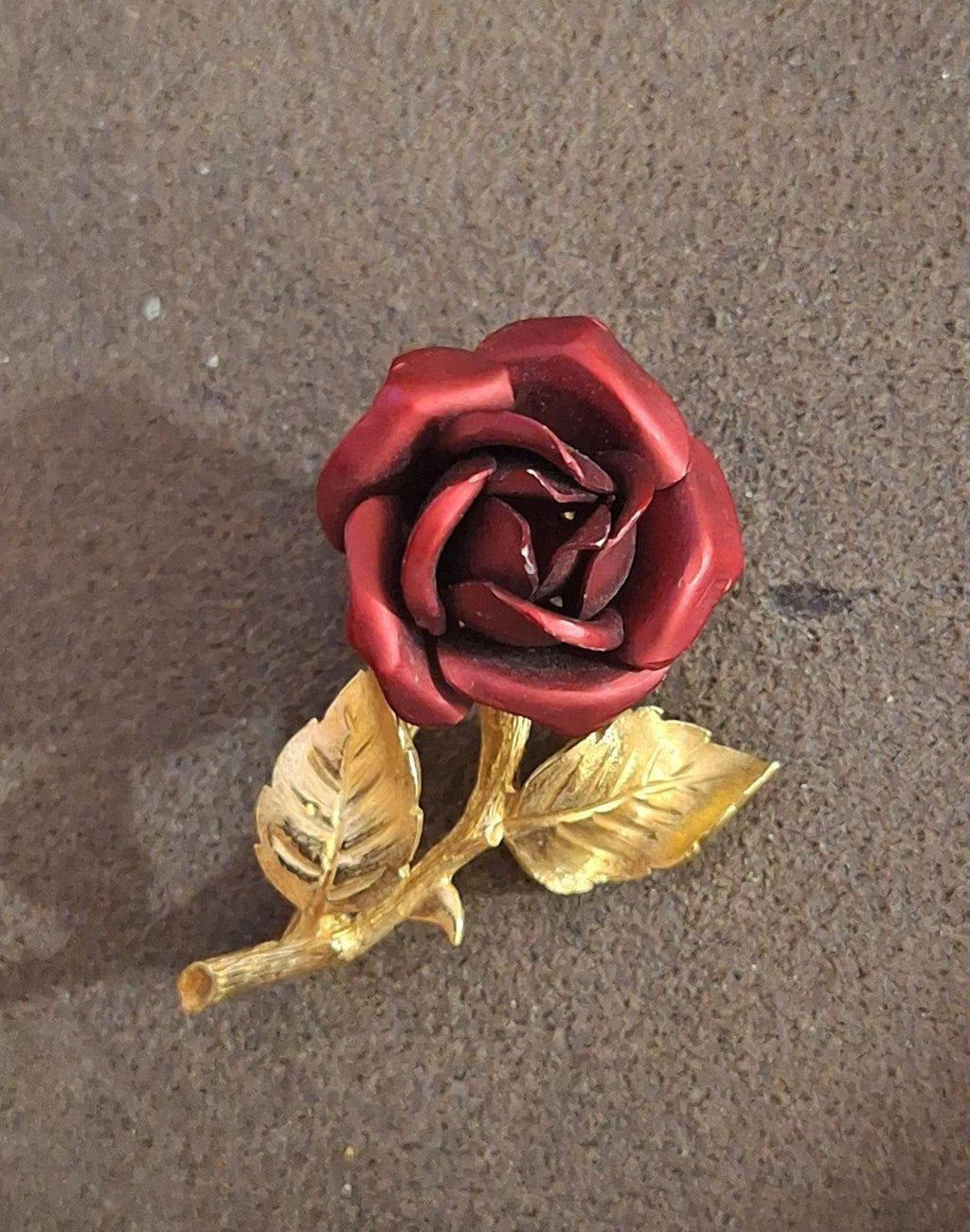 Gold-tone red rose enamel pin brooch with raised leaves and stem, straight-on.