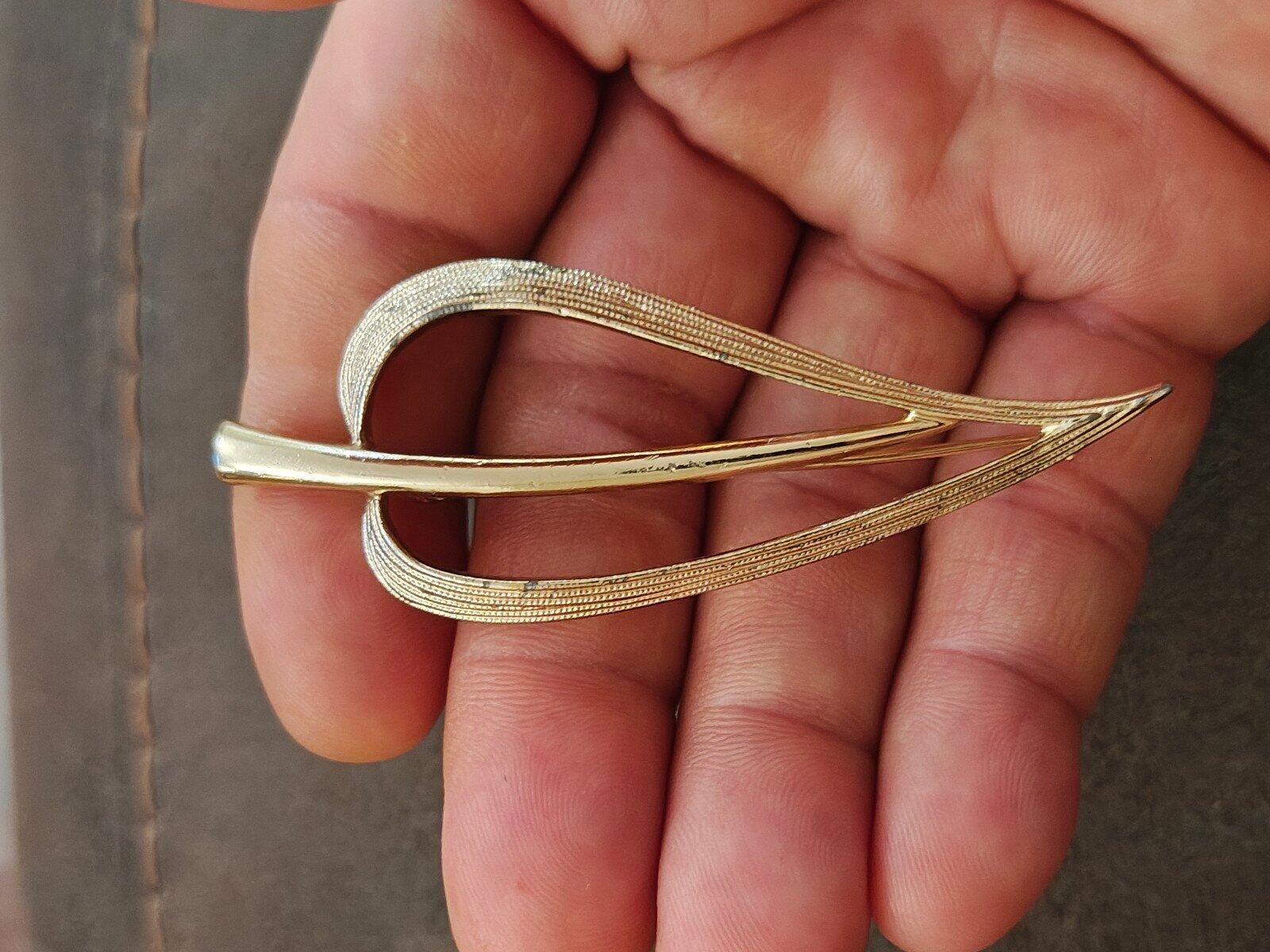 Gold open leaf brooch side view with layered curved bands and pointed tips.