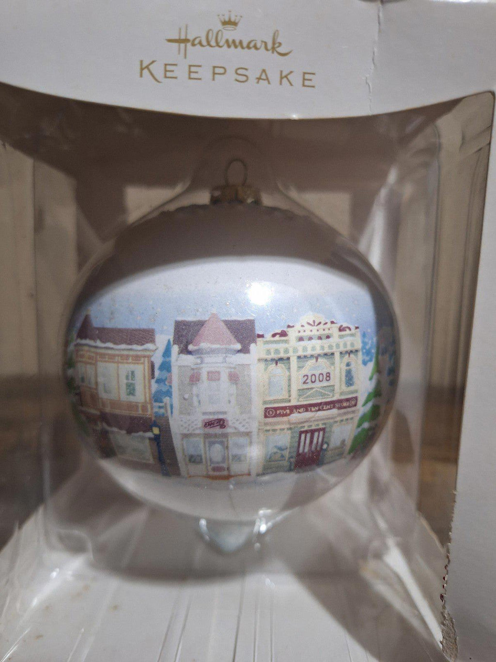 Hallmark Keepsake teardrop ornament showing Main Street buildings and trees in a clear bauble