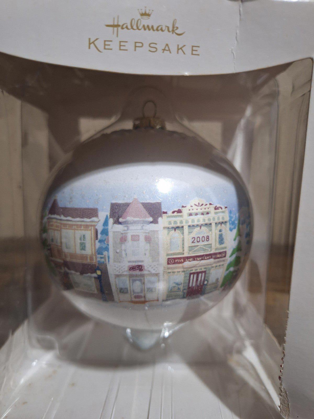 Hallmark Keepsake teardrop ornament showing Main Street buildings and trees in a clear bauble