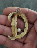 Gold-tone monogram pendant with raised letter D, pearl drop, and silver-tone bail