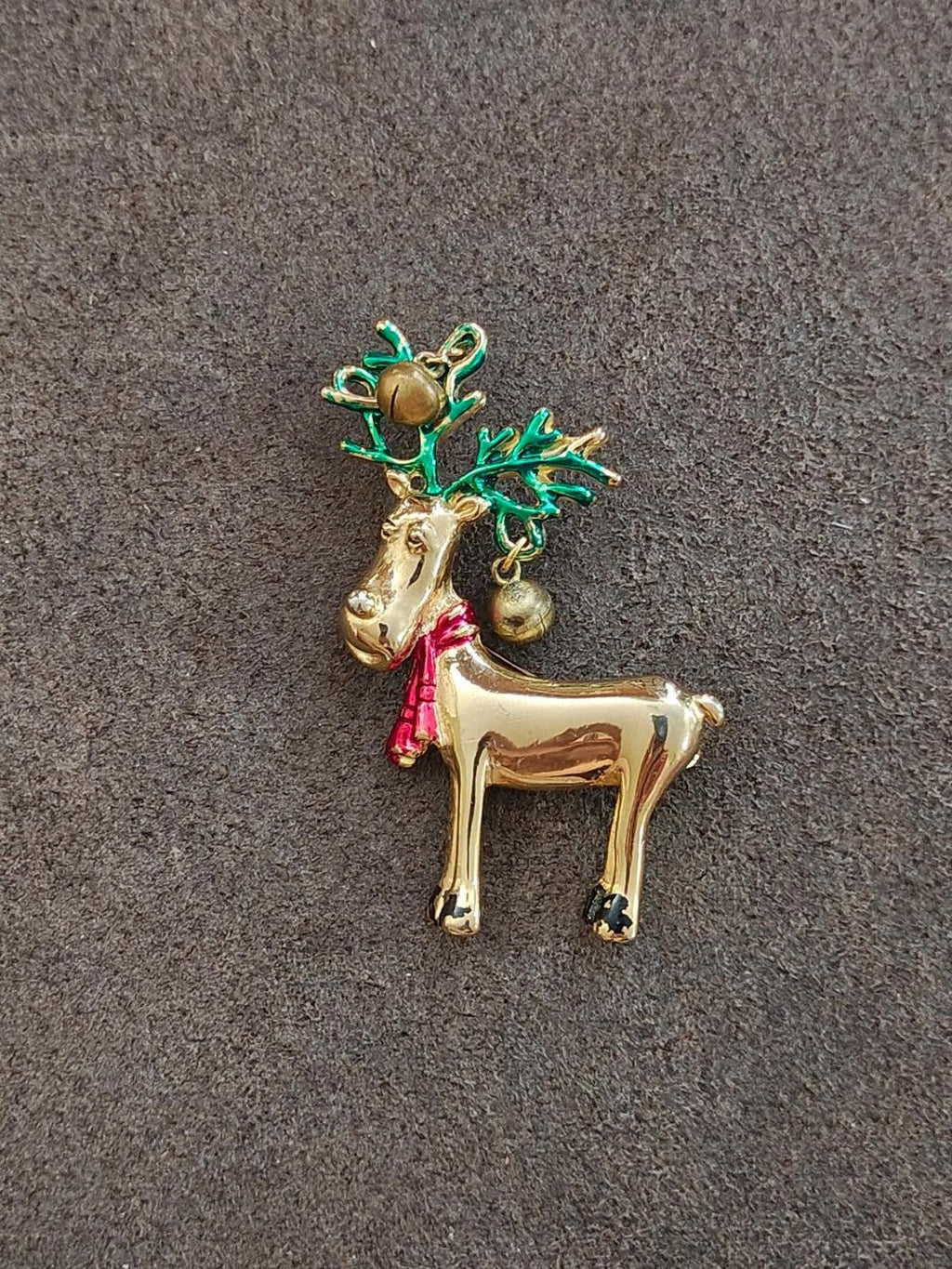Gold-tone reindeer pin brooch on fabric, green antlers and red scarf with bells.