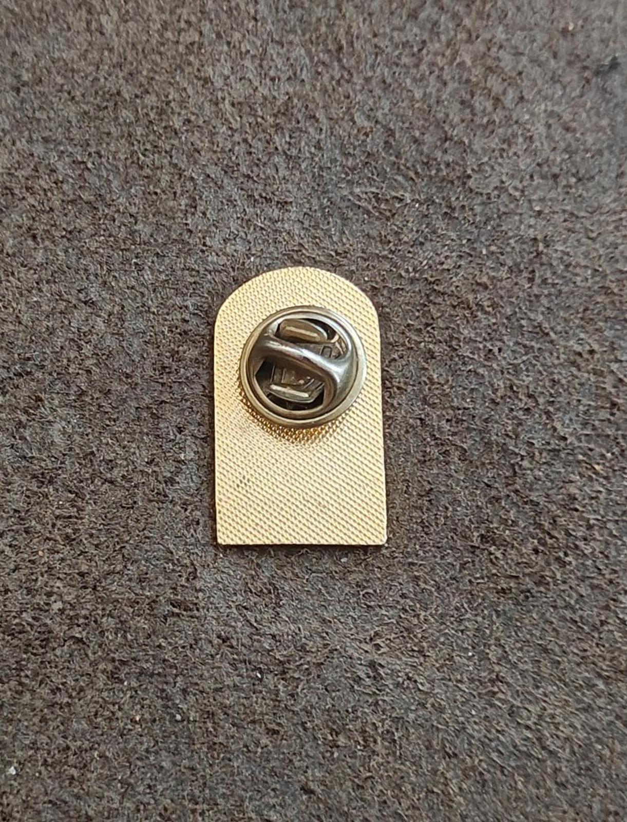 Gold-tone metal teacher pin back with clasp on textured tan backing card