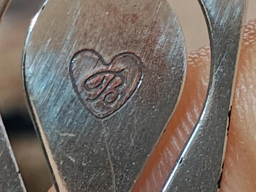Silver plated letter opener close-up of heart-shaped engraving on the blade