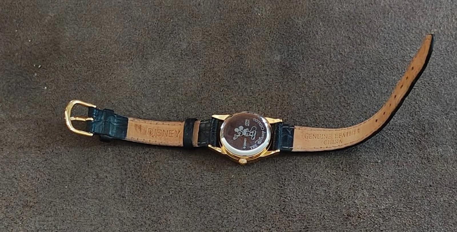 Quartz wristwatch with round gold case, blue leather strap, and buckle, flat lay.