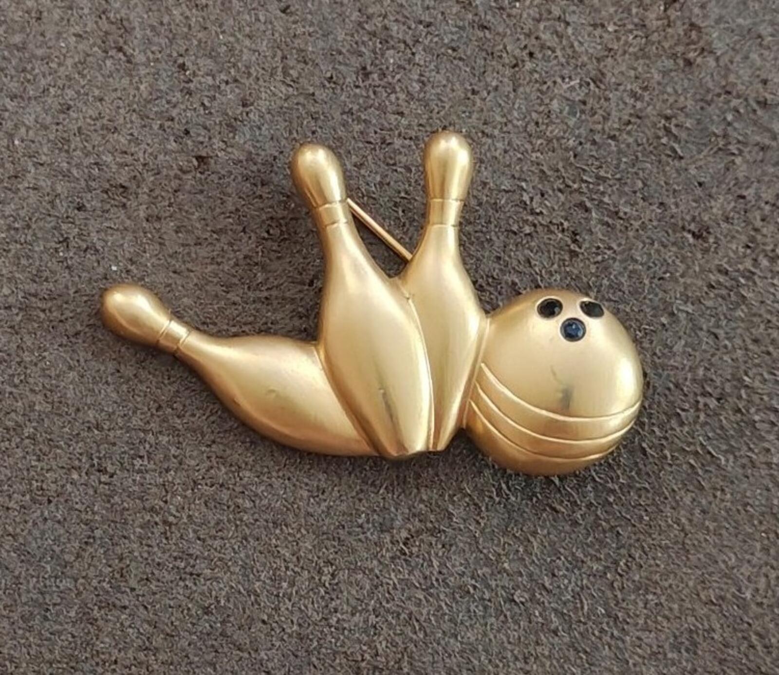 Gold-tone bowling pin and ball brooch with painted ball face, angled close-up