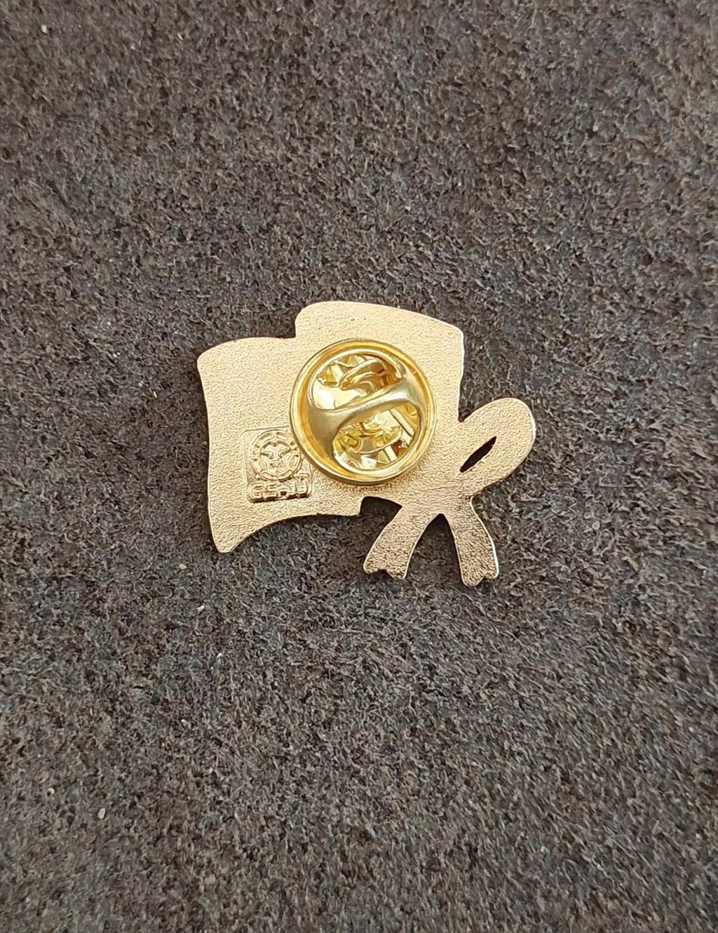Back of gold-tone lapel pin with clasp and small stamped details