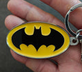 Batman oval logo keychain charm with yellow border, black bat symbol, silver ring visible