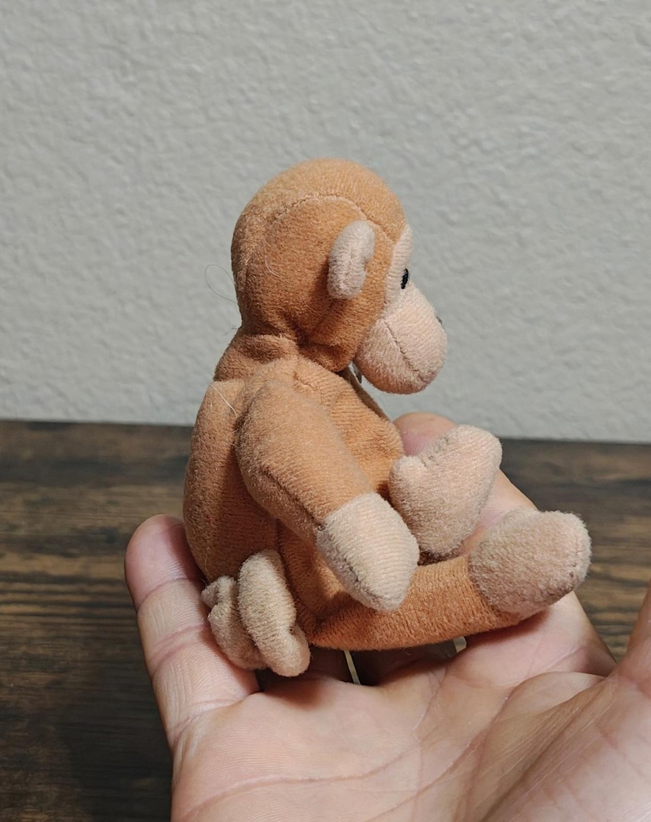 Brown plush monkey side view with little feet, held in open hands