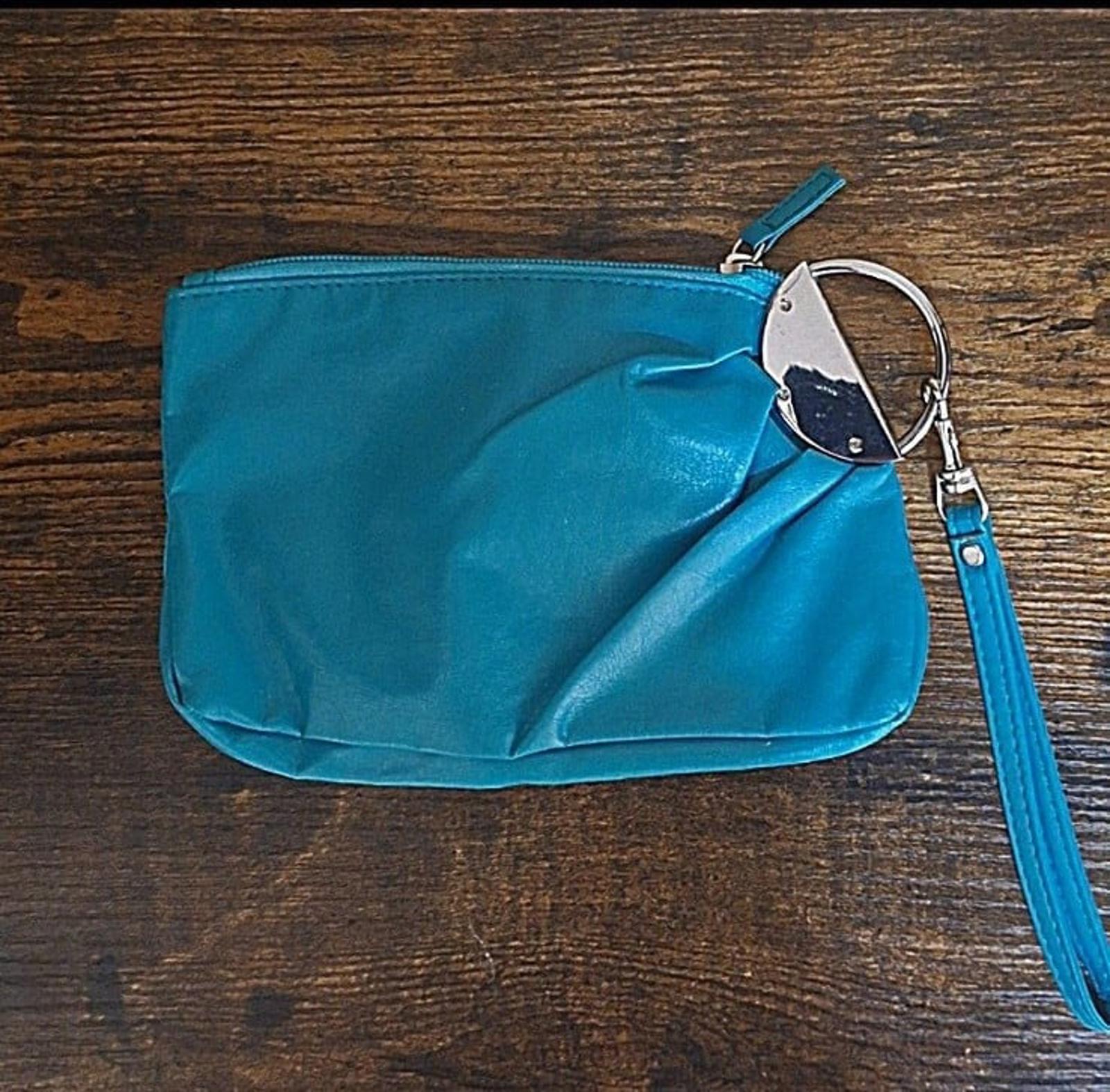 Teal PVC clutch purse with zipper and metal ring handle, angled view