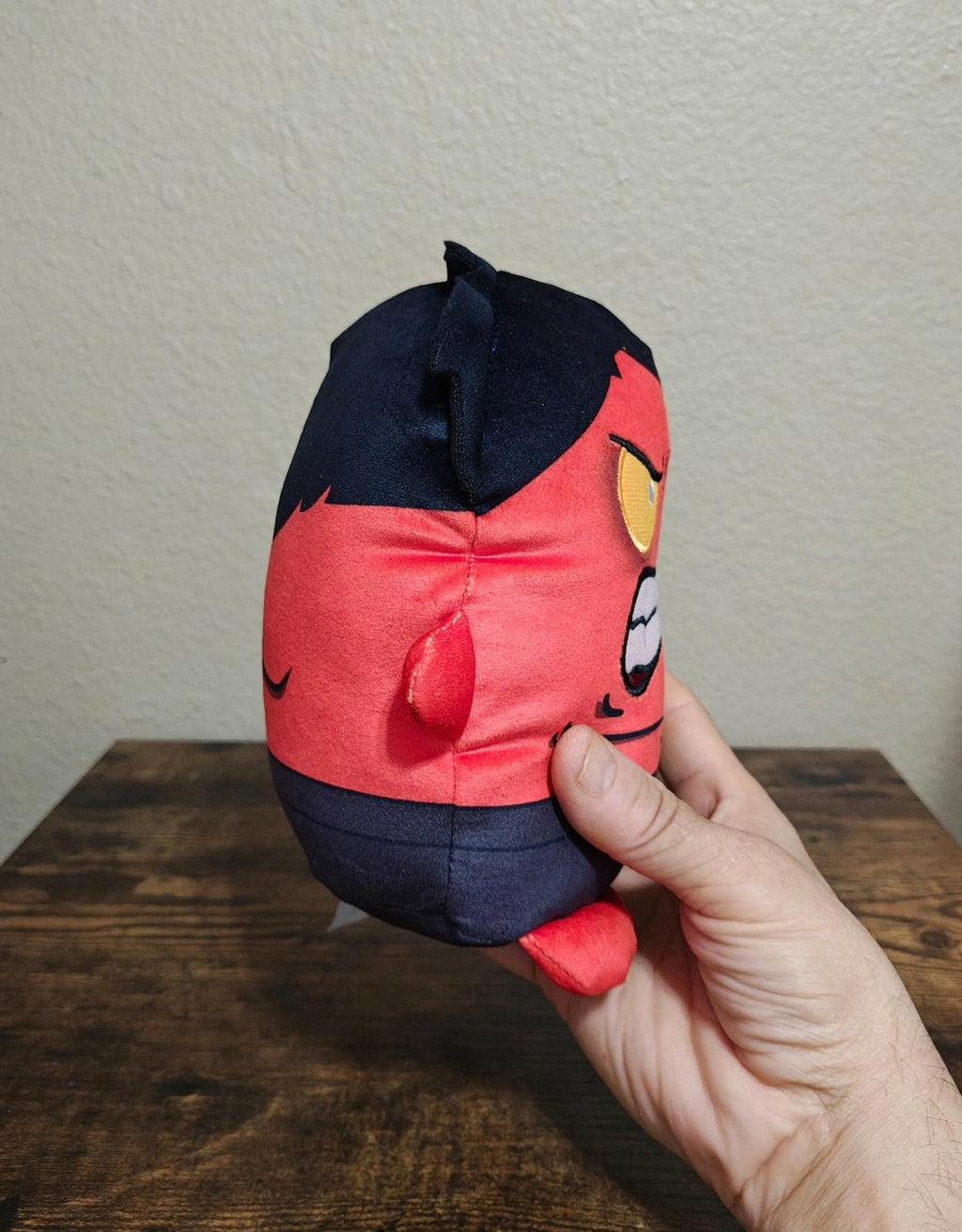 Close side view red and navy plush character with embroidered facial details