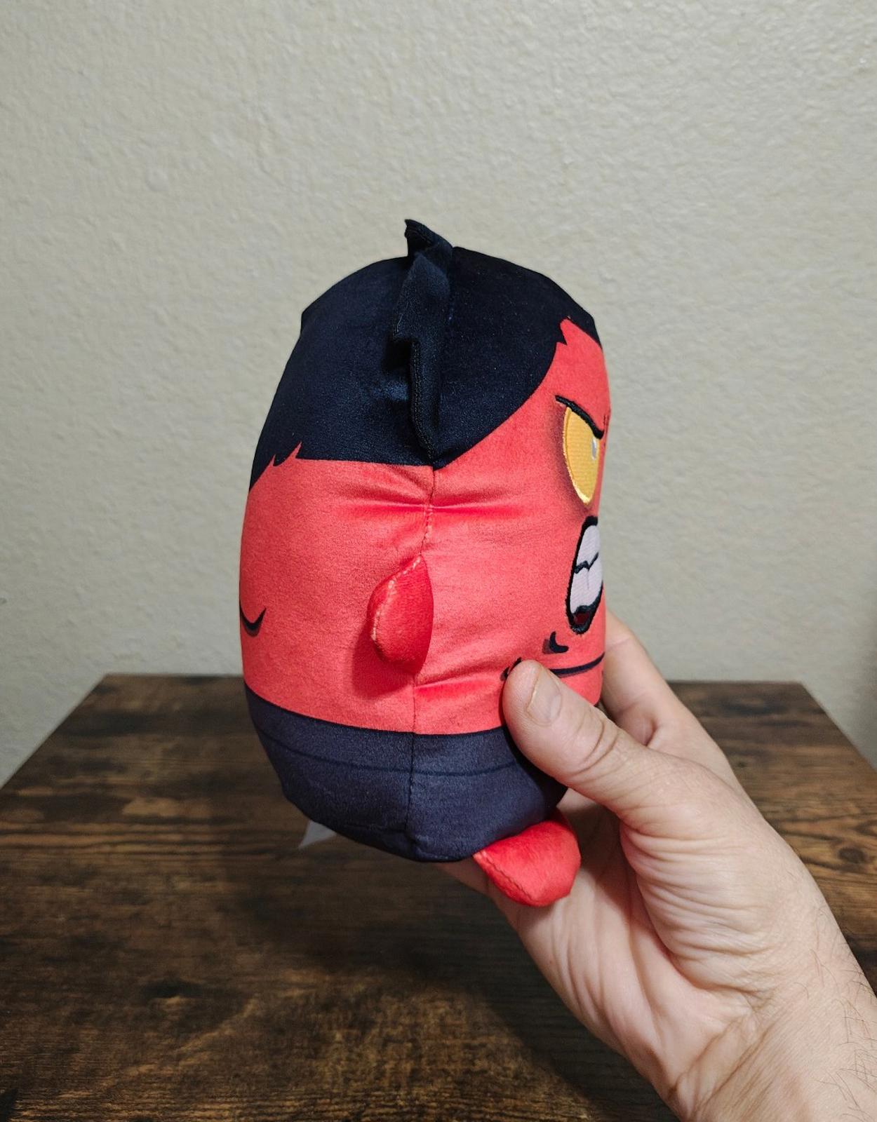 Close side view red and navy plush character with embroidered facial details