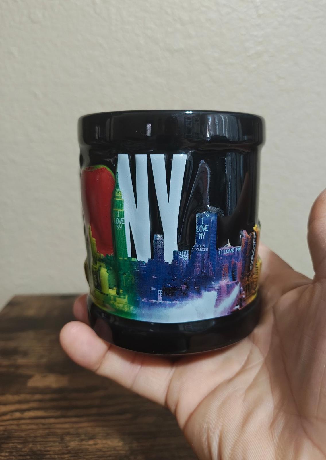 Black ceramic mug with colorful skyline graphic and glossy finish, front view