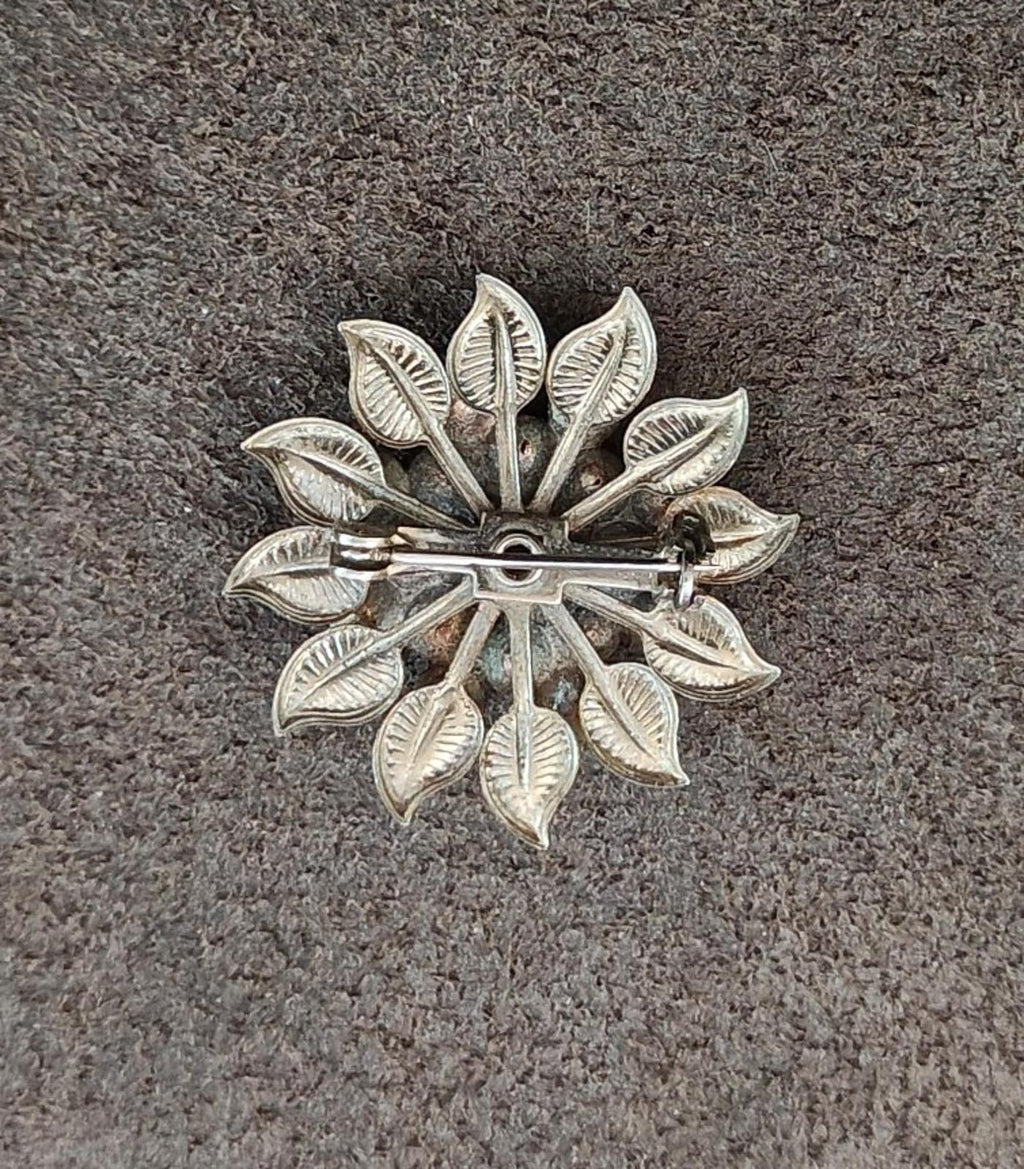 Silver-tone flower brooch back with pin and clasp, ornate leaf design.