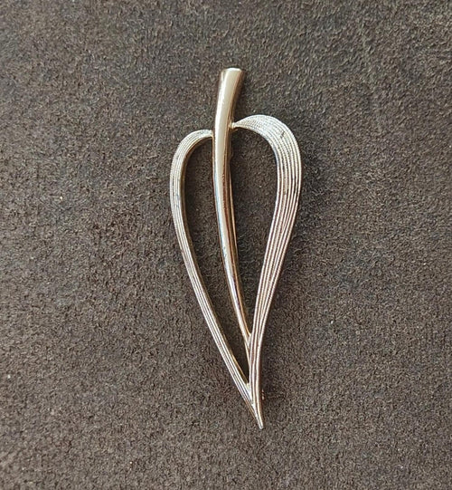 Gold open leaf brooch with slim center stem and raised textured border.