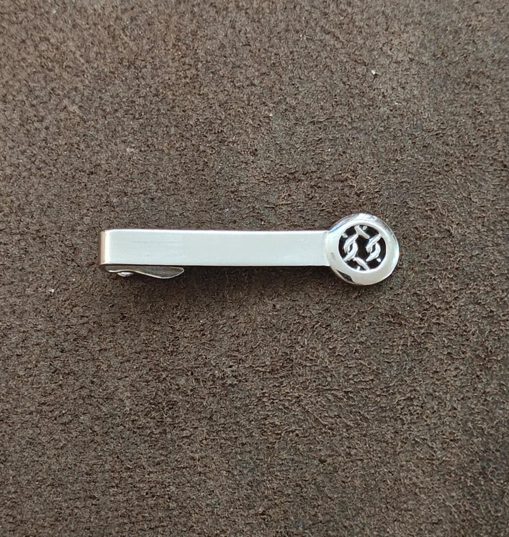 Silver tie bar clip laid flat, round Celtic knot medallion end