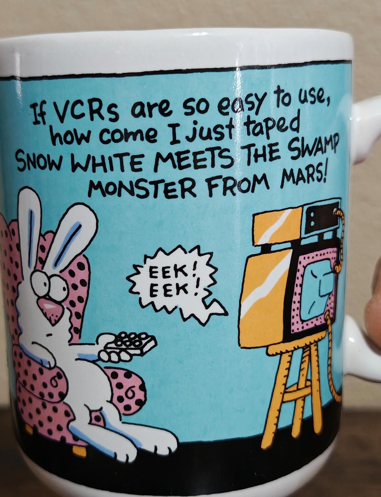 Blue ceramic mug close-up with VCR text, cartoon rabbits, and retro TV illustration