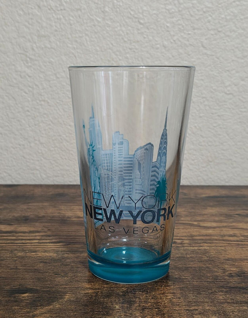 Clear pint glass with blue skyline print, 'New York as Vegas' text, blue base