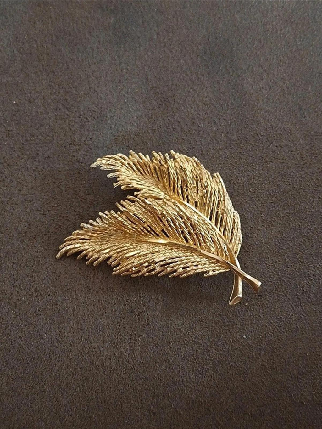 Gold-tone feather and leaf pin brooch with two layered feather shapes, shown flat