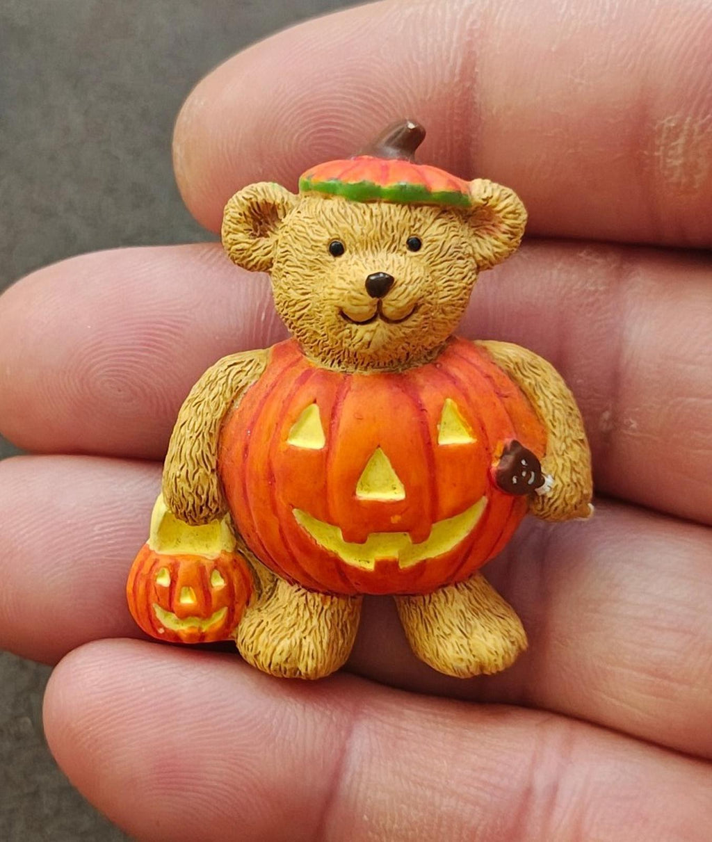 Yellow teddy bear brooch in orange jack-o'-lantern costume with green cap
