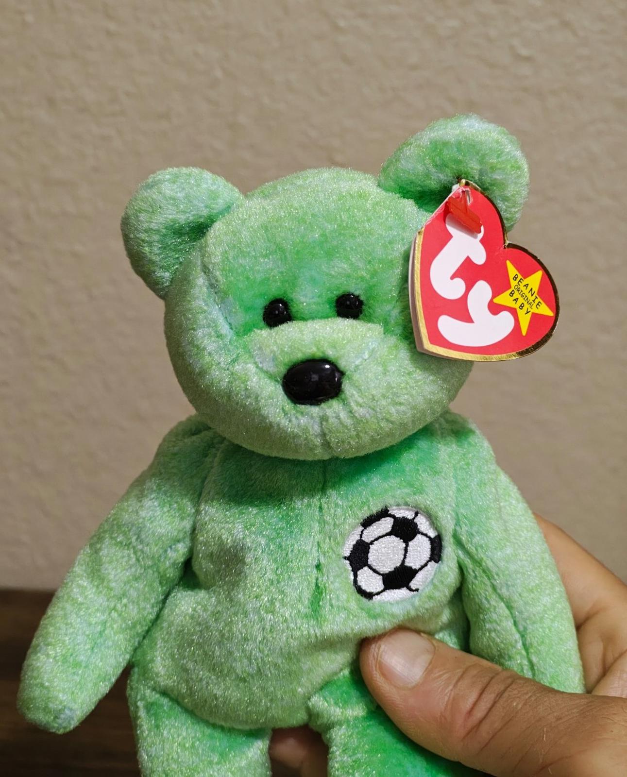 Green teddy bear plush with embroidered eyes, soccer ball patch, and red TY heart tag.